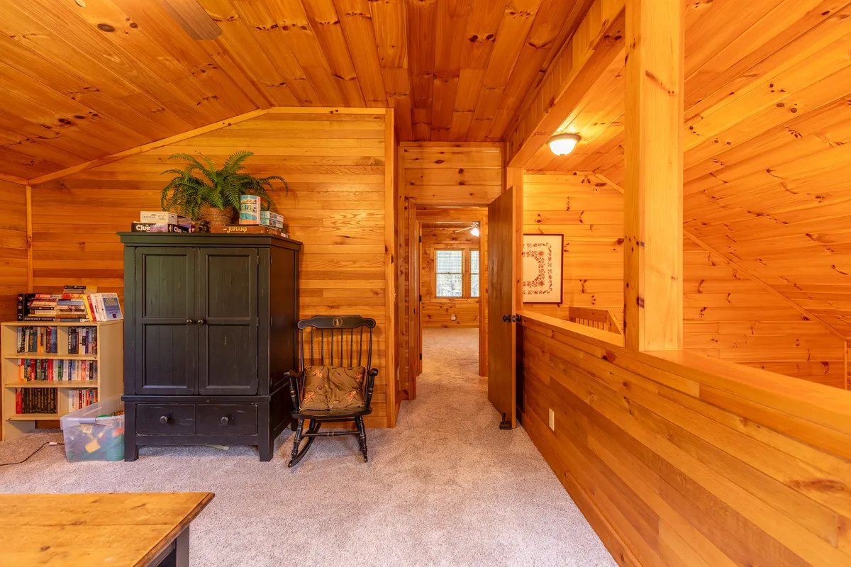 A warm, inviting nook featuring a wooden cabinet, rocking chair, and a bookshelf, suggesting a cozy corner ideal for reading, storytelling, or creative downtime. The soft lighting and wood accents add to its tranquil vibe.