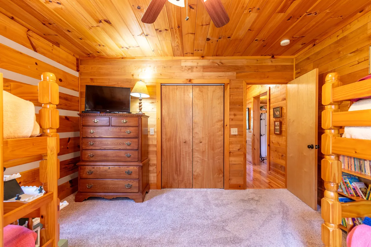 This image presents a child-friendly area with bunk beds, a wooden dresser, lamp, and closet doors. The space feels playful yet comfortable, suitable for both quiet play and shared family moments.